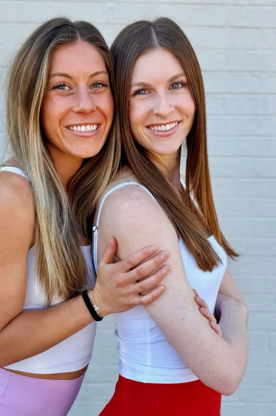 Kenzie Damm with a fellow Sozo Wellness trainer against a white brick wall in Denver